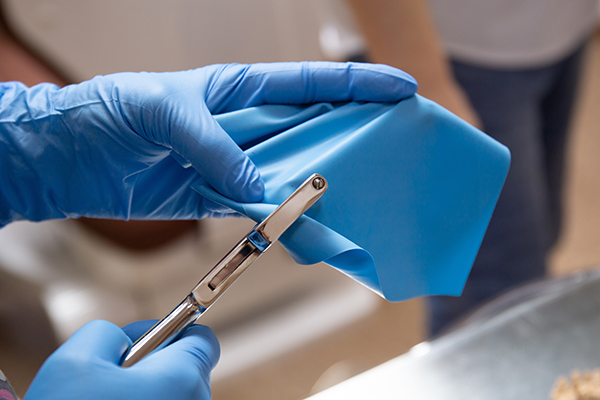 reduces-downtime-product-costs A medical professional’s hands in rubber gloves, manipulating a rubber medical sheet
