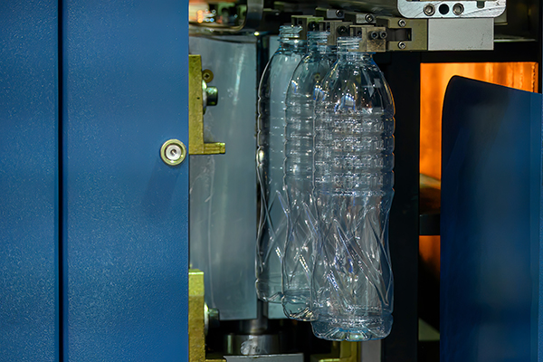 AdobeStock_705759595 Plastic bottles held in a blow molding machine