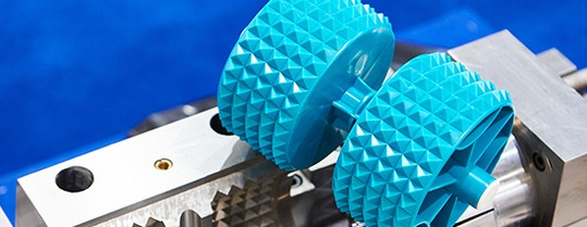 Two blue textured rollers mounted on a metal bracket.