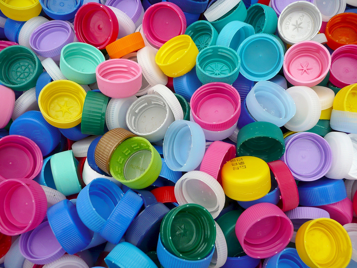 Various colors and styles of bottle caps in a pile.
