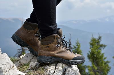 A person wearing hiking boots and standing on a mountain rock ledge.