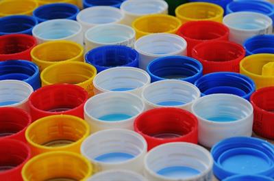 Lined up plastic caps to beverage bottles of all colors
